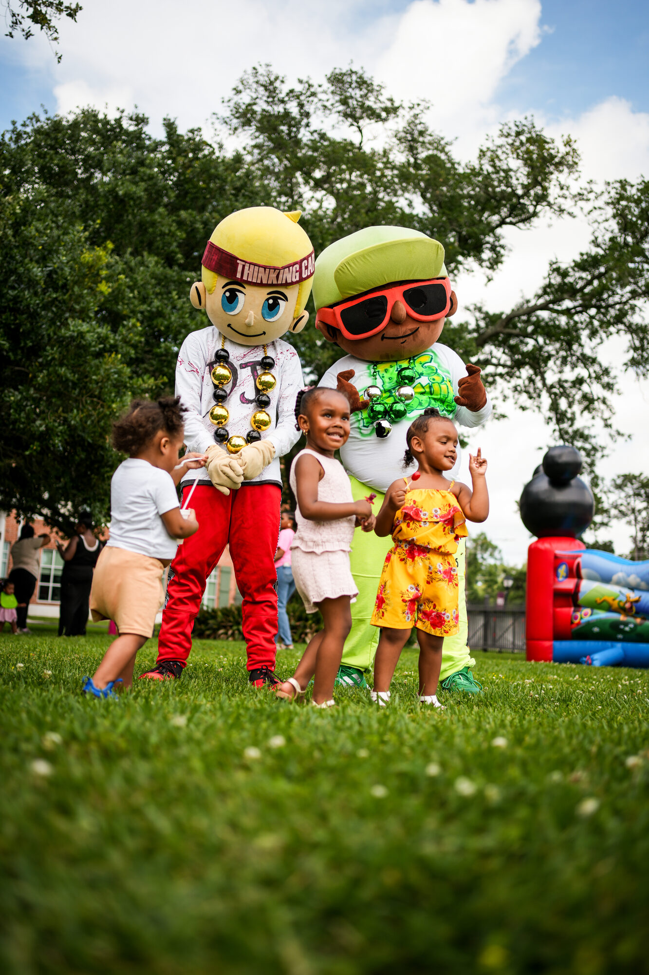 Children playing with costumed characters on the grass